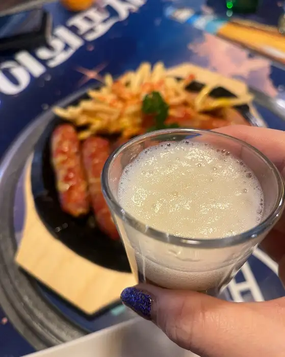 맥주가 담긴 잔과 흐릿하게 보이는 소시지 요리