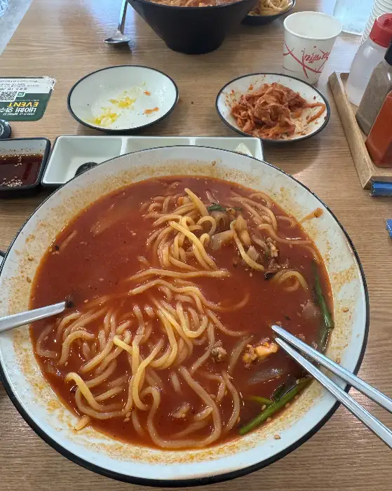 테이블 위에 놓인 짬뽕, 짜장면, 탕수육, 김치, 단무지, 간장 등의 음식 상차림