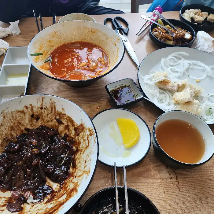 테이블 위에 놓인 다양한 음식들과 식기류, 집게, 가위 등
