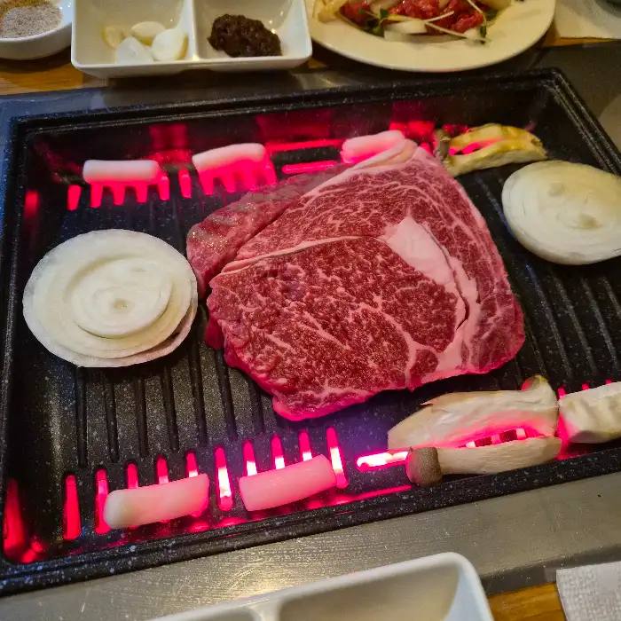 불판 위에서 익어가는 소고기와 곁들임 채소