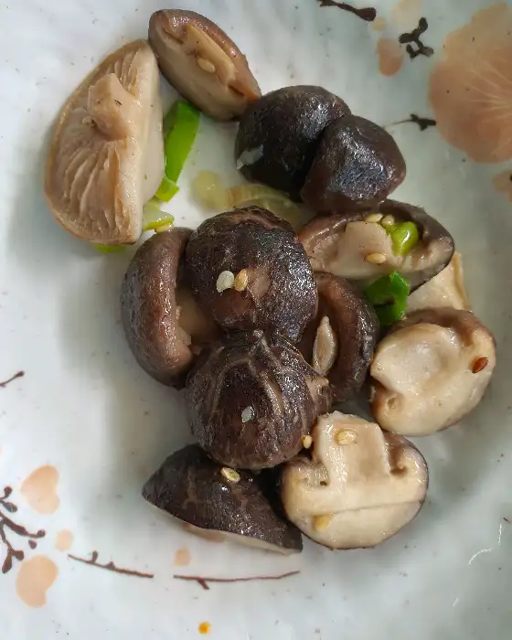 접시에 담긴 버섯 요리. 표고버섯과 다른 종류의 버섯들이 볶아져 있다.