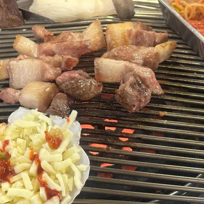 치즈가 얹어진 가리비와 구워지는 고기