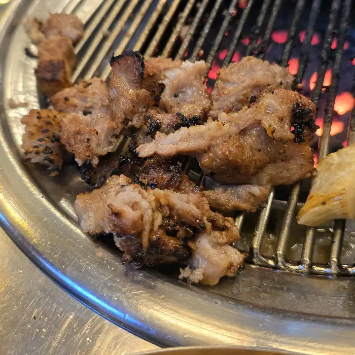 다양한 부위의 돼지고기가 불판 위에서 구워지고 있는 모습