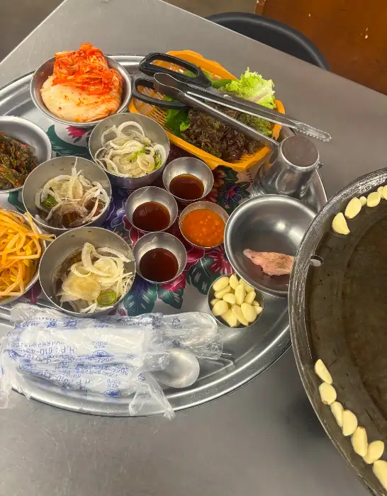 잘 구워진 삼겹살 조각과 쌈 채소, 소스가 담긴 모습