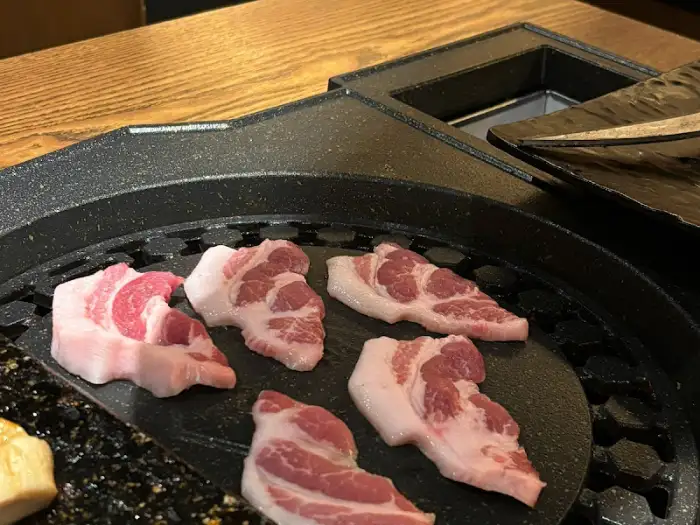 불판 위에 정갈하게 올려진 생삼겹살 조각들