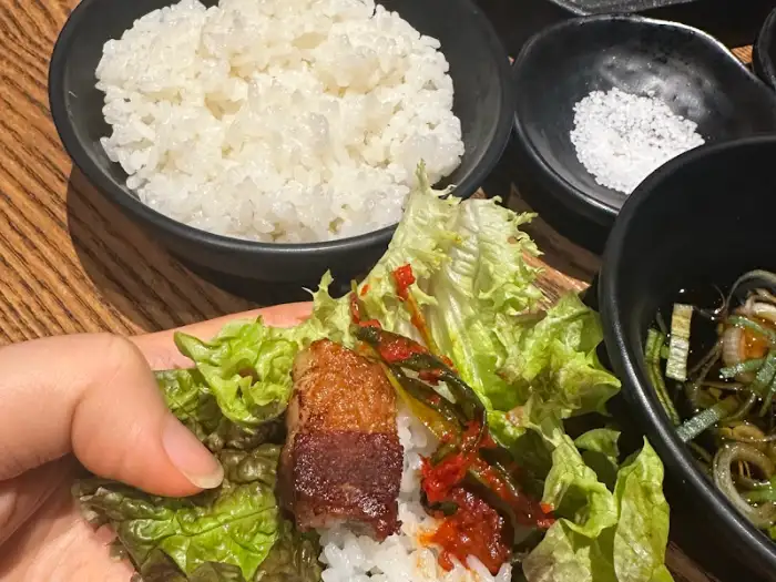 상추 위에 밥, 고기, 채소, 고추장을 곁들여 푸짐하게 쌈을 싸놓은 모습