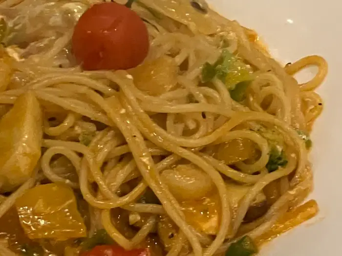 접시에 담긴 파스타 클로즈업 사진. 얇은 면발에 크리미한 소스가 묻어있고, 위에 방울토마토 하나가 올라가 있다.