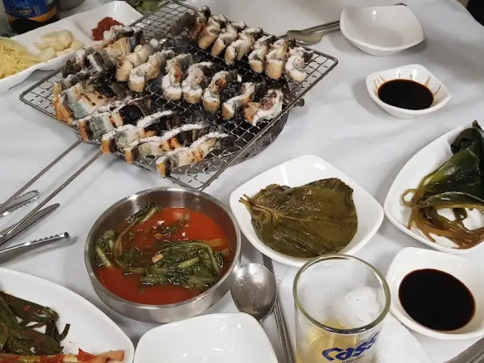 장어구이가 올려진 철망, 장어탕, 깻잎 장아찌, 생강채, 간장 소스 등 상차림이 보인다.