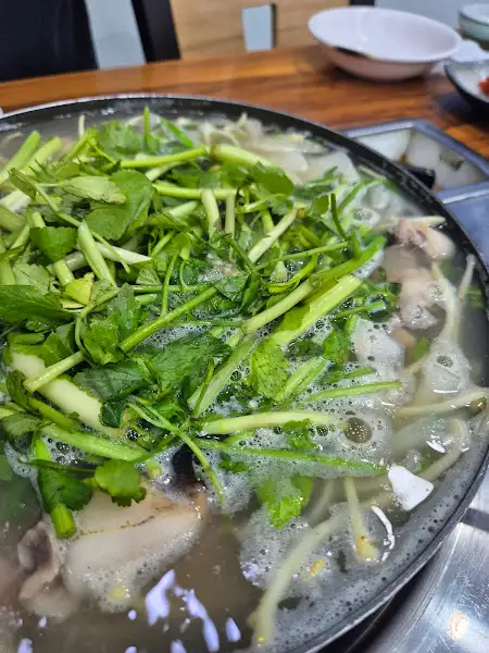 끓고 있는 장어탕에 신선한 채소가 가득 올라가 있다.