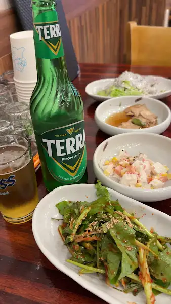 테이블 위에 놓인 맥주병과 여러 가지 곁들임 메뉴들