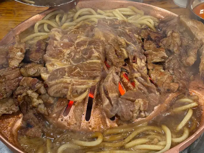 숯불 위에서 익어가는 돼지갈비와 우동사리