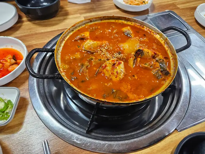 철판 위에 올려진 갈치조림 냄비와 주변의 밑반찬들