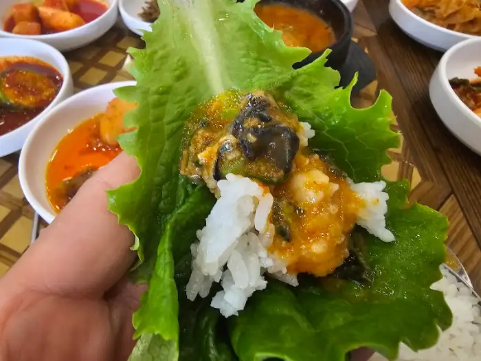 쌈 채소에 쌈장과 밥을 얹어 먹기 좋게 싼 모습