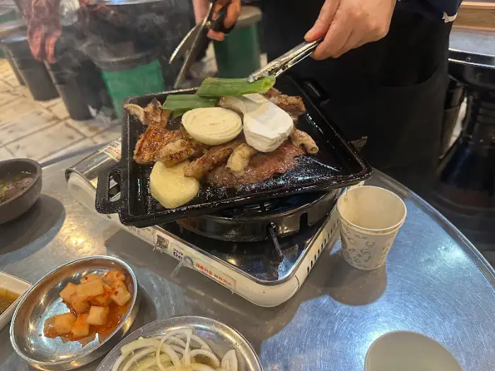 불판 위에서 익어가는 곱창과 채소, 그리고 곁들임 찬