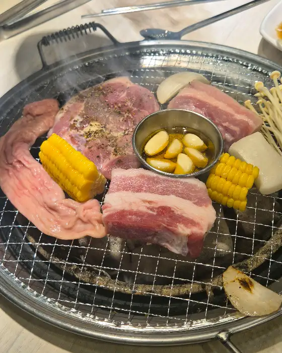 먹음직스럽게 익어가는 삼겹살과 곁들임