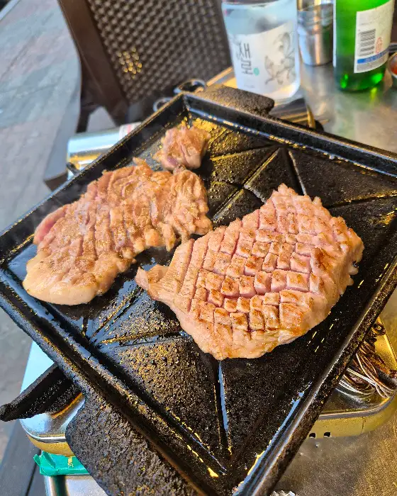 두툼한 두께의 오겹살이 불판 위에서 익어가고 있습니다.