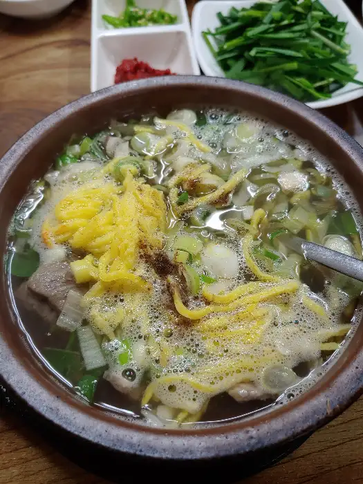 그릇에 담긴 맑은 국물의 해장국. 노란 계란 지단이 올려져 있음.