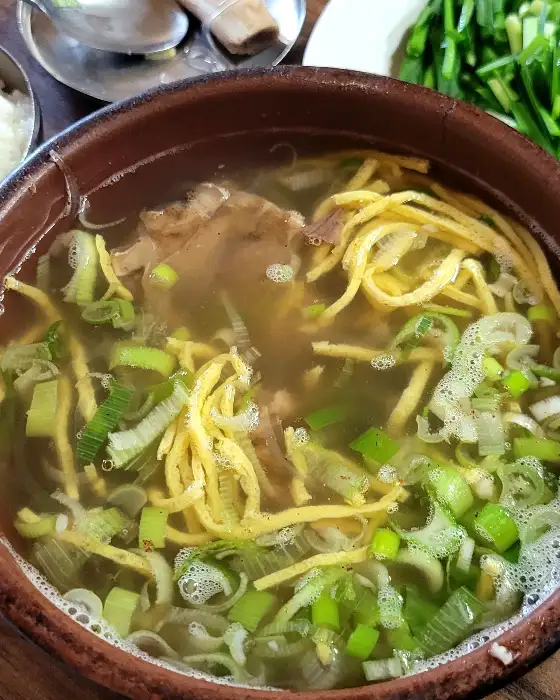 그릇에 담긴 맑은 해장국. 얇게 썬 파와 계란 지단이 보임.