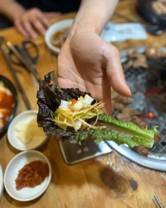 잘 구워진 돼지갈비 한 점을 젓가락으로 집어 올리는 모습