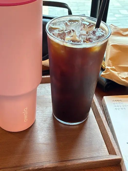 디디씨돌담커피 산동점 중심부의 식물 조형물과 테이블 배치