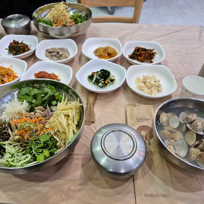 많은 종류의 반찬과 비빔밥, 탕이 차려진 식탁