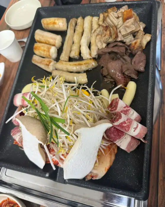 무쇠판에 구워지고 있는 곱창과 부속고기, 숙주, 감자 등의 모습