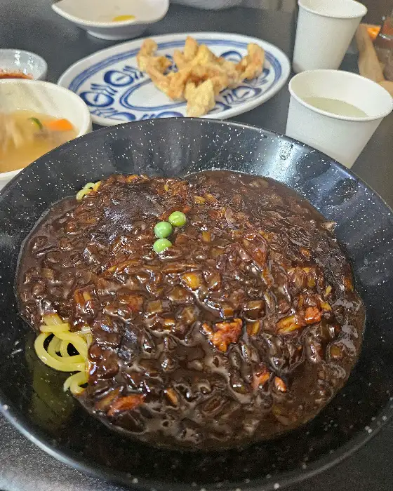 쟁반짜장 소스가 면 위로 부어지는 모습