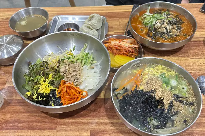 두 가지 종류의 칼국수와 육회비빔밥, 김치, 젓갈이 놓인 상차림