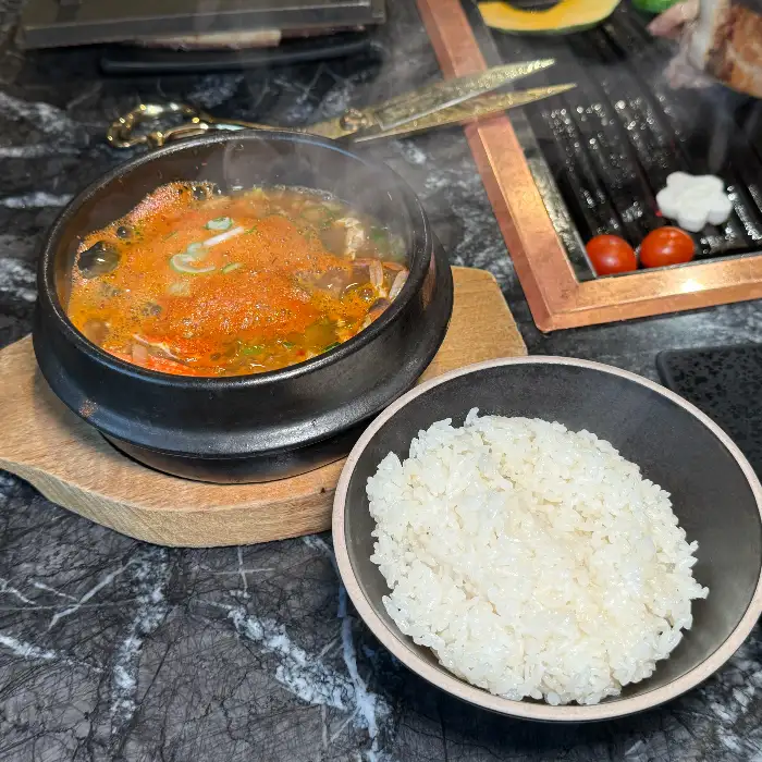 김이 모락모락 나는 뚝배기 찌개와 밥 한 공기
