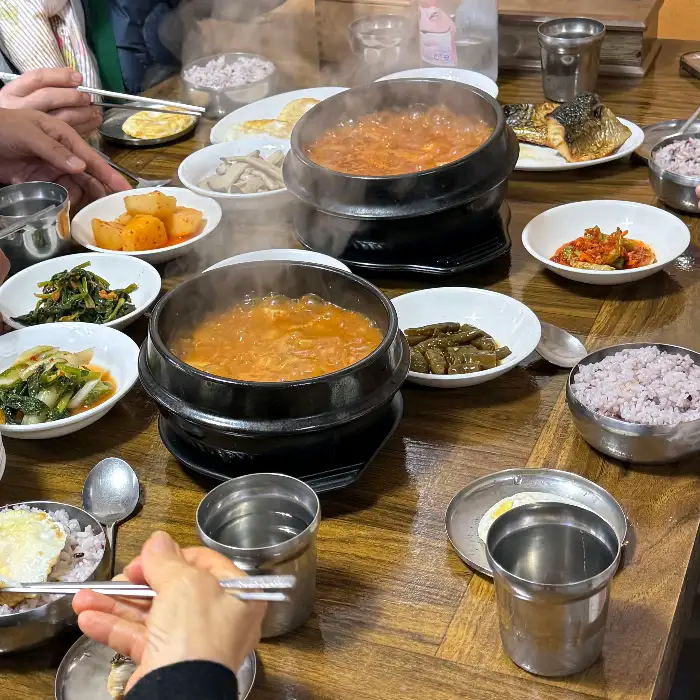 김이 피어오르는 뚝배기 찌개 두 개와 밥