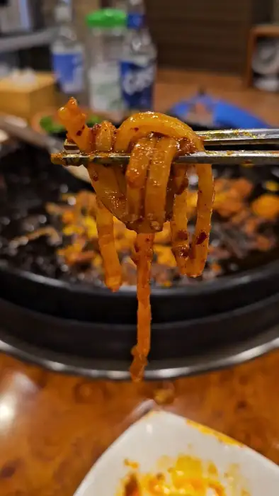 집게로 집어 올린 먹음직스러운 닭갈비