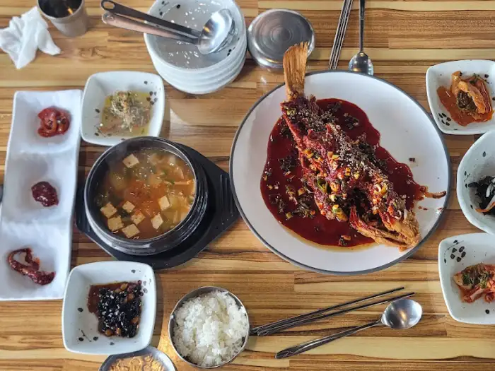 테이블에 가득 차려진 음식들, 우럭튀김, 물회, 밥, 국, 그리고 다양한 반찬
