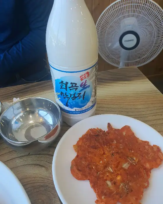 김치전 위에 놓인 막걸리 병과 잔.
