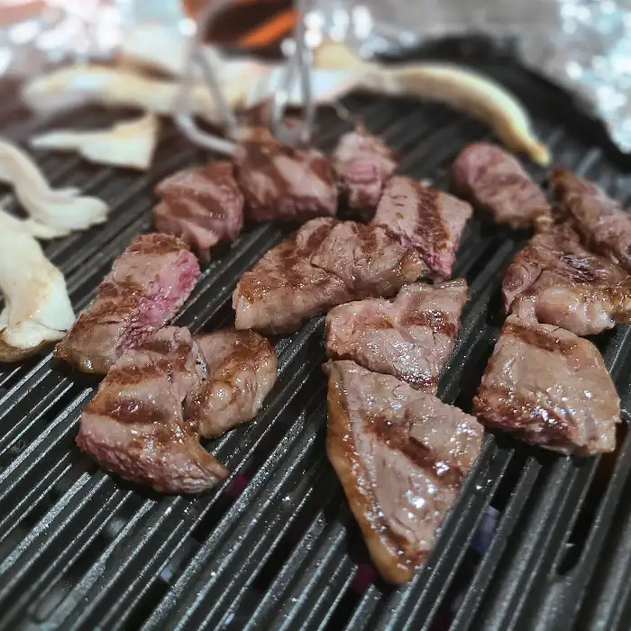 잘 구워진 한우 고기 조각들이 접시에 담겨 있는 모습
