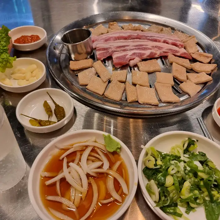 한상 가득 차려진 삼겹살과 곁들임 메뉴들