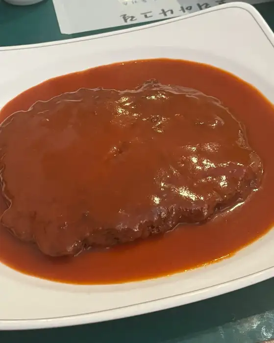 두툼한 김치치즈돈까스에 소스가 넉넉히 부어져 있는 모습