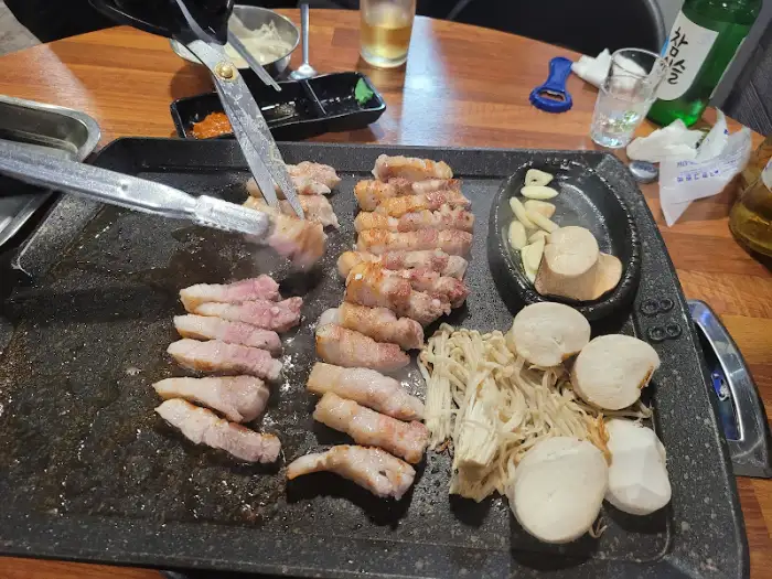 불판 위에서 익어가고 있는 삼겹살과 버섯, 마늘