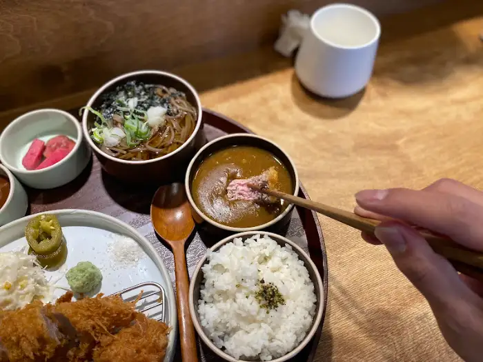 카레 국물에 카츠 조각을 찍는 모습