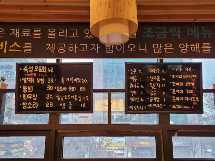 메뉴판에 적힌 글씨가 보이는 모습. 다양한 해산물 요리 이름과 가격이 적혀 있습니다.