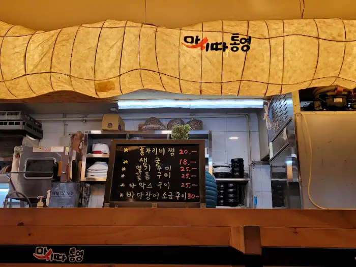 작은 칠판에 적힌 메뉴들. 꼬막 비빔밥, 김치전, 멸치국수 등의 메뉴가 보입니다.