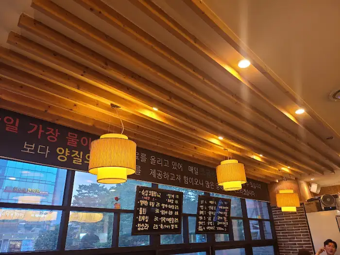 주황색 계열의 갓등 조명 여러 개가 천장에 달려 있는 모습. 나무 천장과 어우러져 따뜻한 분위기를 연출합니다.