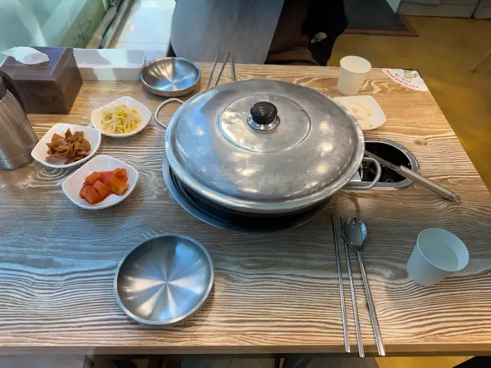 테이블 위에 놓인 덮개 덮인 냄비와 반찬 그릇들