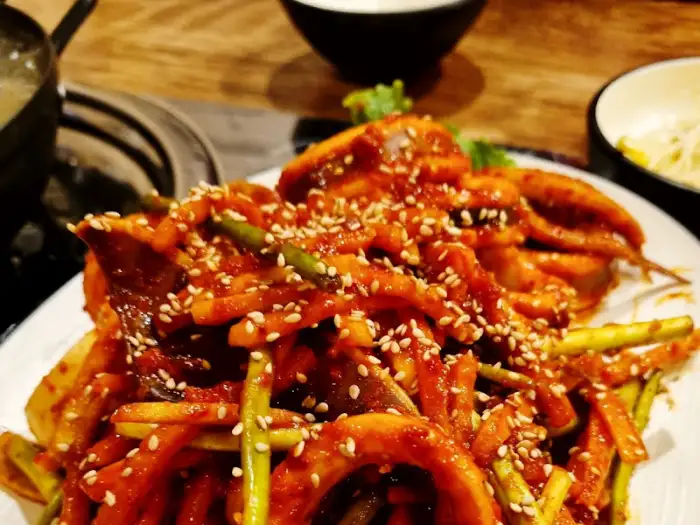 오징어볶음 위에 뿌려진 깨와 곁들여진 채소