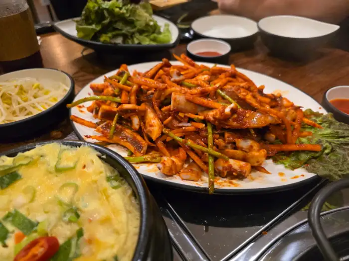 테이블에 차려진 다양한 음식들, 오징어볶음과 탕 등이 보인다