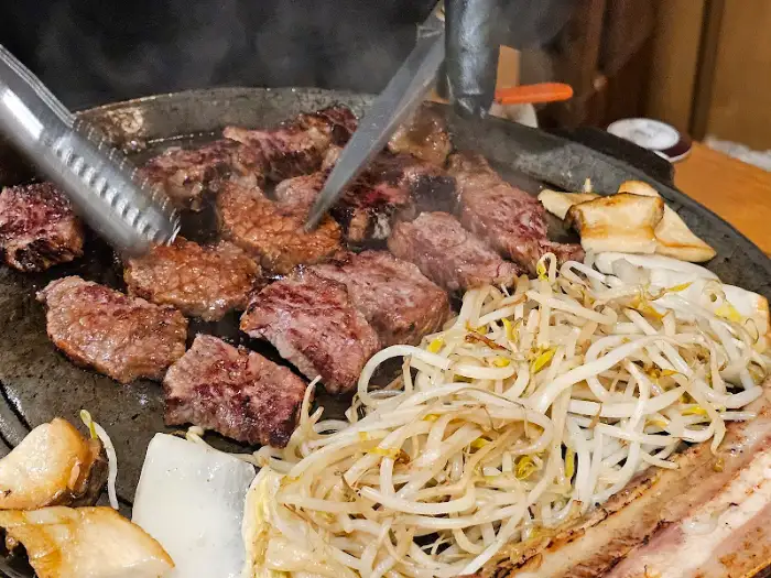 불판 위에서 구워지는 다양한 부위의 소고기와 콩나물