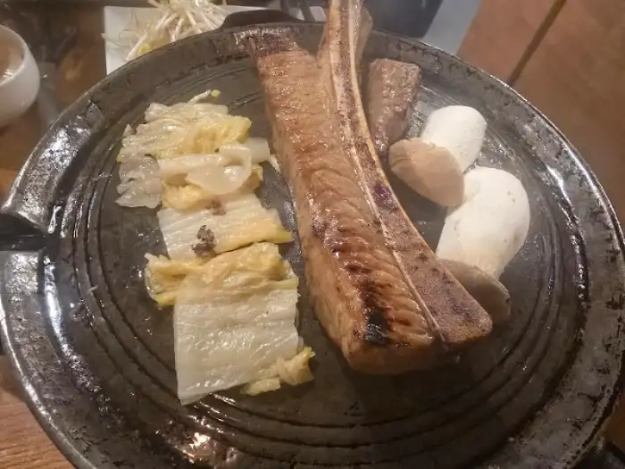 두툼한 우대갈비와 곁들임 채소가 함께 놓인 불판