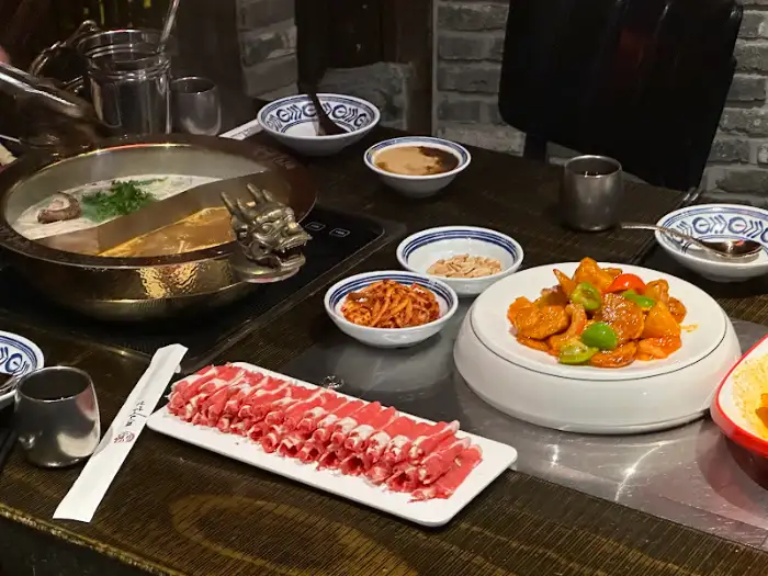 훠궈 냄비와 신선한 고기, 다양한 채소가 차려진 식탁