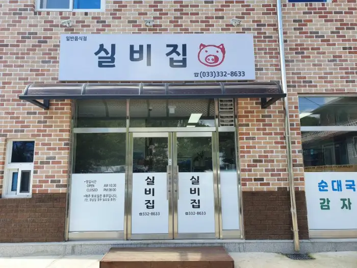 건물 입구, '실비집'이라는 간판과 함께 붉은 벽돌 건물이 보입니다.