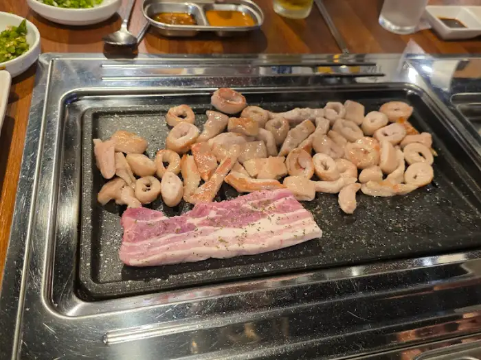 철판 위에서 막창과 함께 돼지 삼겹살이 함께 구워지고 있는 모습. 다양한 메뉴를 한 번에 즐길 수 있다.