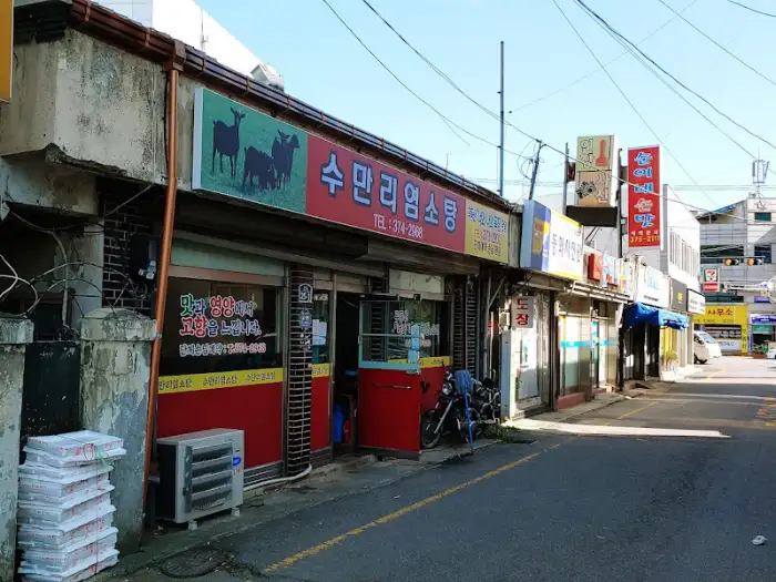 수마리 염소탕 식당 건물의 외부 모습. 1층에 위치해 있으며, 여러 상점들과 함께 줄지어 있다.